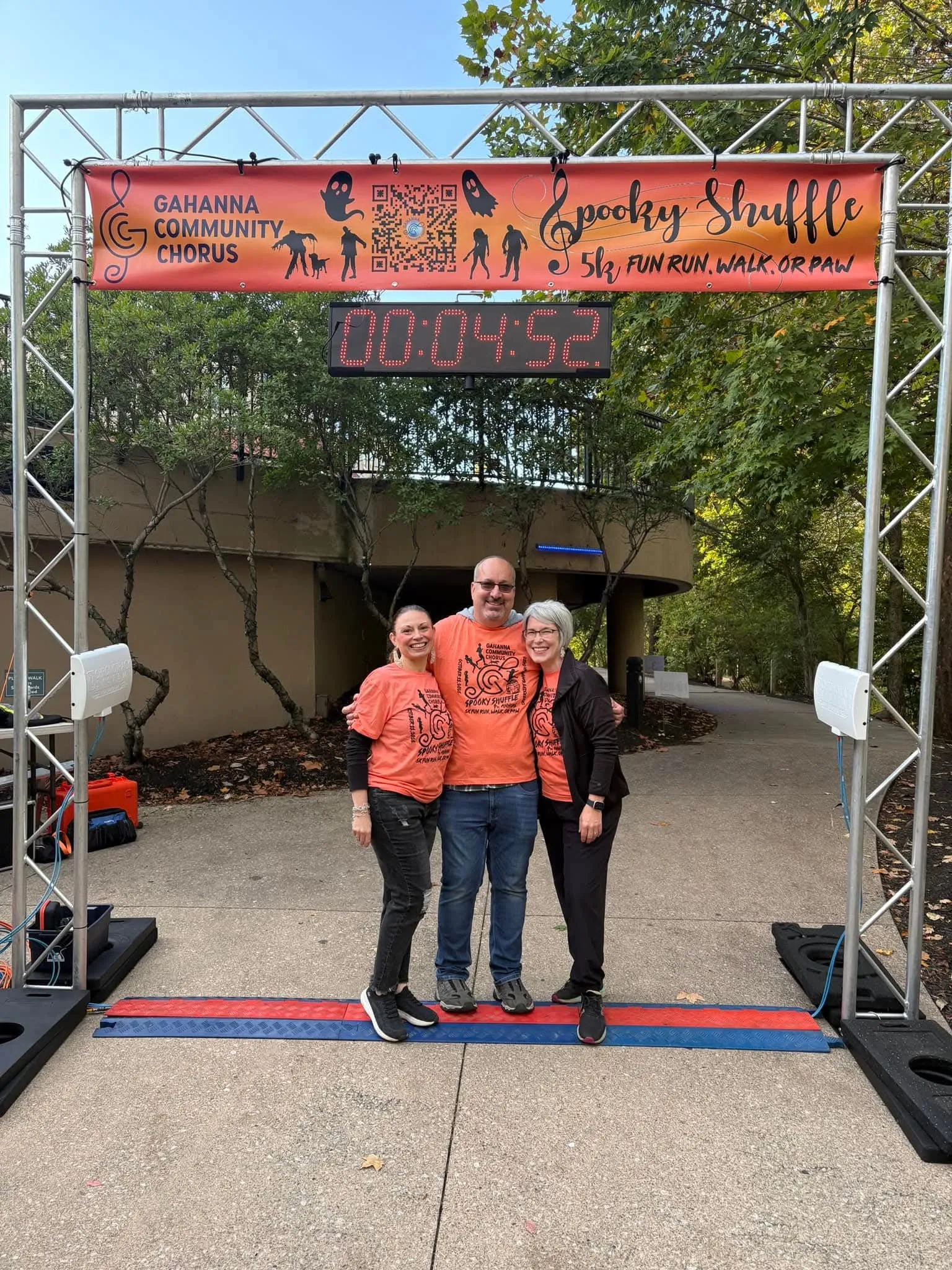 Kendra, Troy, and Kate posing in front of the spooky shuffle 5k start