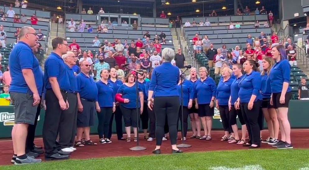 a wide shot of the gahanna community chorus singing the national anthem at a columbus clippers baseball game