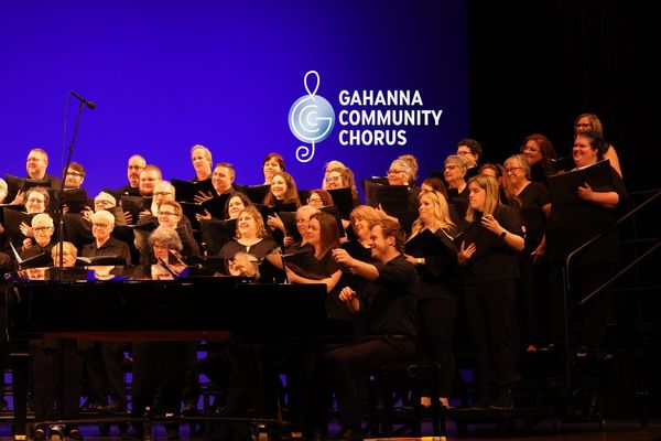 a full shot of the gahanna community chorus singing one of their concerts with the chorus accompanist, Nate Terry, in the foreground at the piano
