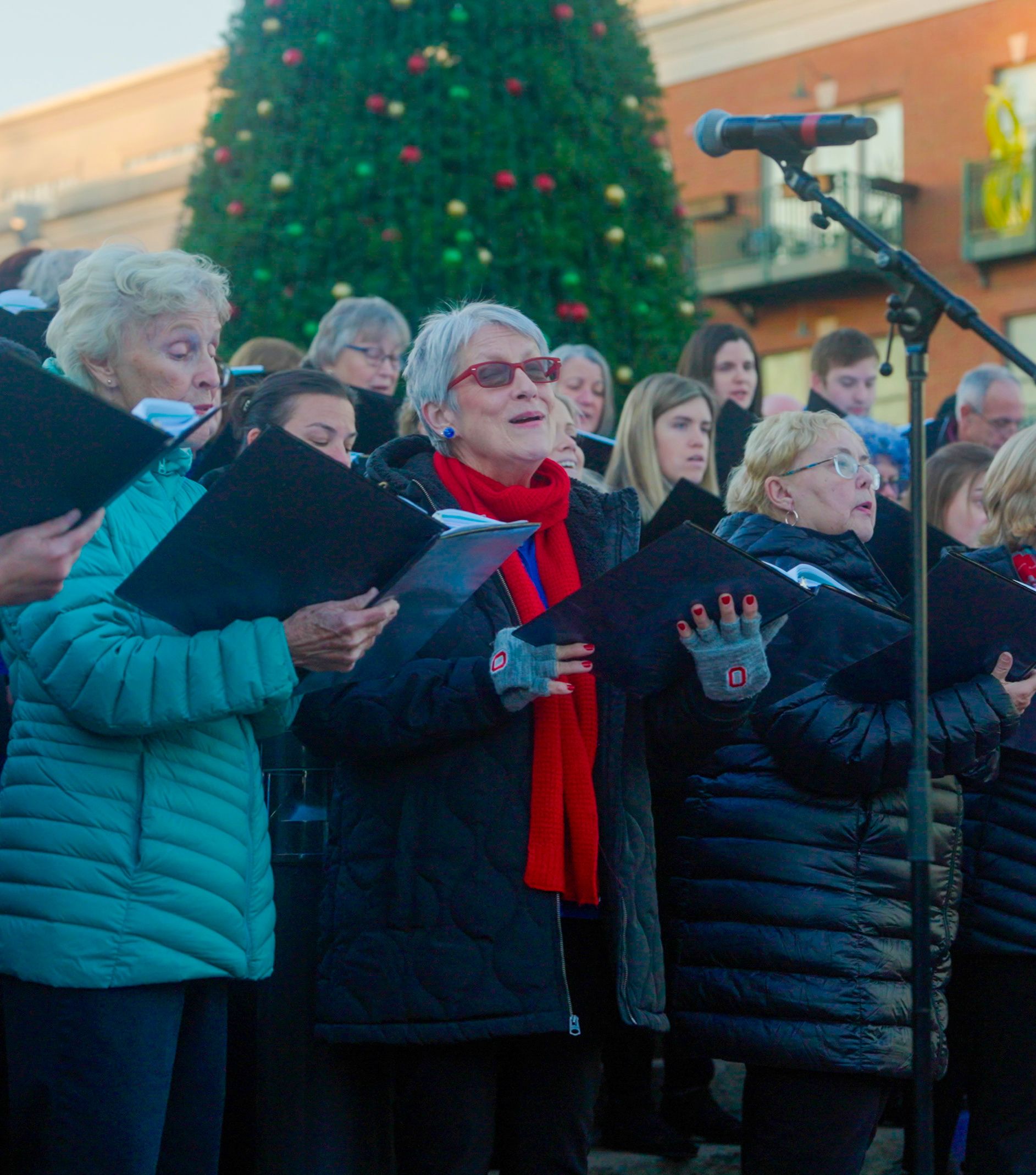 focused shot of a gahanna community chorus member singing joyously at the holiday lights celebration hosted at creekside in gahanna ohio