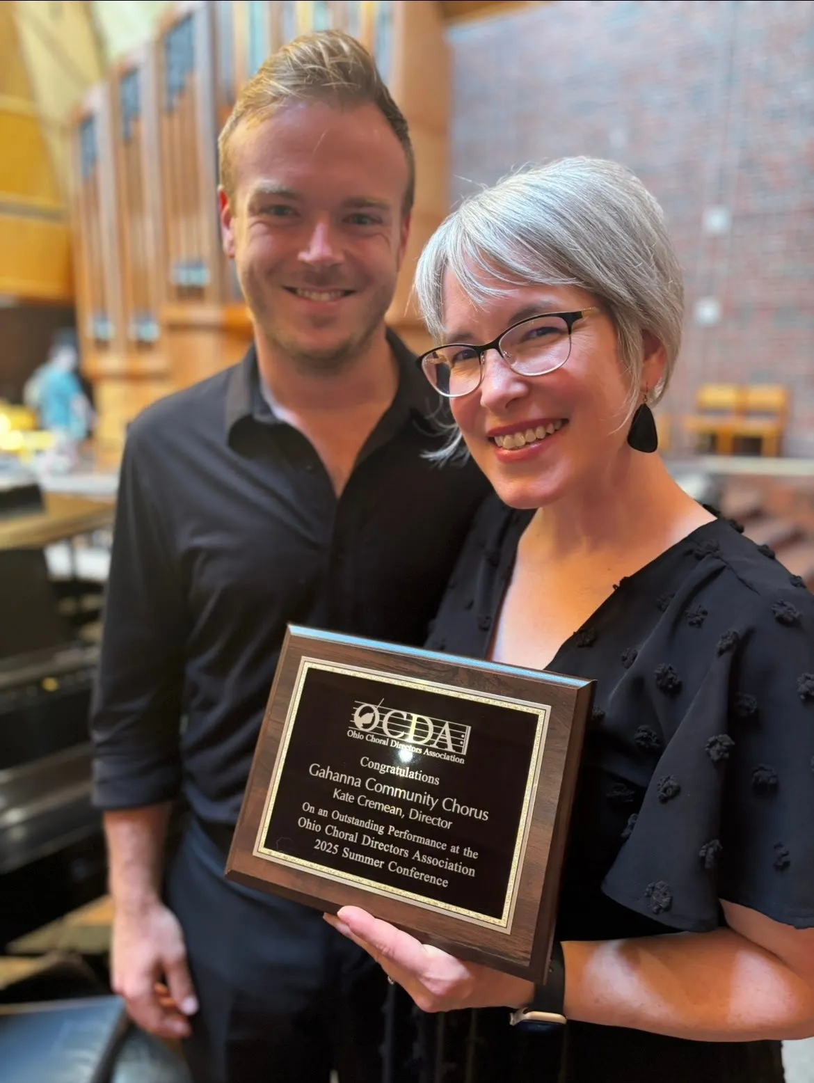 kate cremean accepting the Ohio Choral Directors Association outstanding performance plaque with the chorus's pianist, nate terry